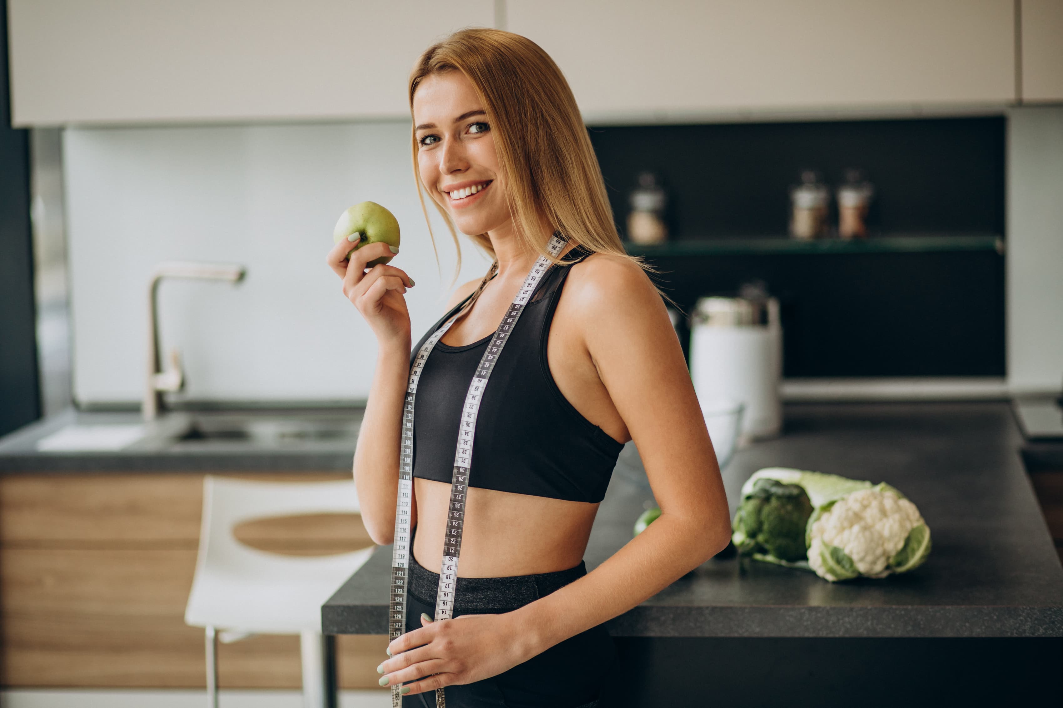 Woman in athletic wear in a modern kitchen, representing integrative wellness